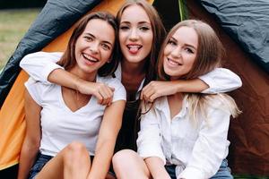 Funny girls hugging and happily smiling sitting in the camping photo