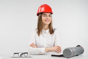 Smiling woman sits at the table in orange hardhat folded her arms photo