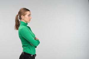 Sideview of a dolorous young woman standing with folded arms isolated on the background. - Image photo