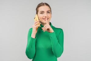 Pretty  young woman talking on a cell phone  and showing silence gesture. - Image photo