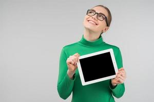 Laughing dreamy woman in the glasses holds  her ipad and looking up photo