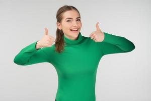 Happy girl standing against white background, holding two thumb up  - Image photo