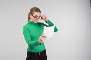 Girl in glasses standing surprised in profile looks on a tablet standing. - Image photo