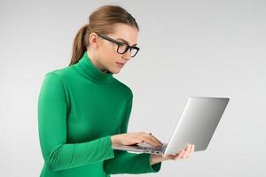 Woman  in profile works on a tablet while standing. Looking carefully at the screen photo