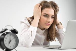 The girl tensely and wearily looks at the laptop, clutching her head with her hands. Gestures  concept photo