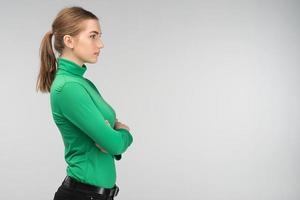 Closeup sideview of a sad young woman standing with folded arms isolated on the background. - Image photo