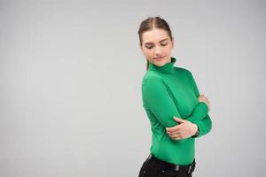 Young girl hugging herself posing in the studio and looking down photo