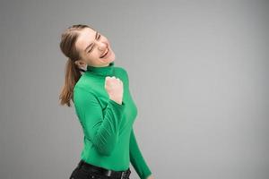 Mujer joven feliz con los ojos cerrados con el puño limpio hacia arriba y sonriendo con la boca abierta.- imagen foto