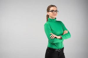 Smiling  young woman  in glasses and in casual clothes posing  with  crossing hands in half-turn . Horizontal image photo