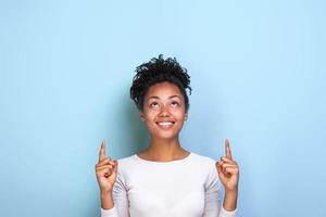 Attractive woman pointing by her both index fingers up to place for copy space