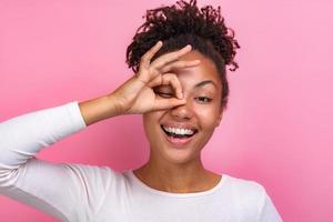 Portrait of a funny girl makes a gesture ok from fingers andlooking through of it closeup - Image photo