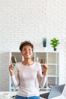 Happy african american woman make a gesture with her index fingers up and looking up pointing to copyspace photo