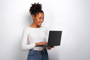 Portrait of girl holding laptop computer and ctyping looking at the screen photo