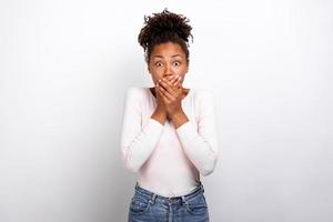 Shocked woman shut mouth with her arms looking at the camera, feel amazed on ligth-grey studio background photo