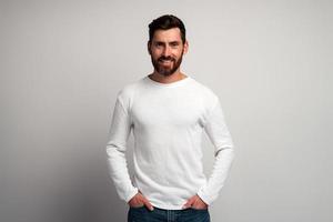 Portrait of happy smiley bearded man with white shirt against light gray background and smiling to the camera. Studio shot. People emotions concept photo