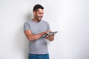 Happy man standing with ipad looking at the screen of it.- Image photo