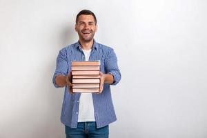 retrato de hombre joven feliz sosteniendo libros en sus manos rectas. De vuelta a la escuela foto