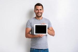 tiro del estudio del hombre feliz que sostiene un ipad con la pantalla en blanco vacía negra. - imagen
