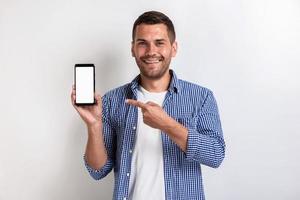 Smiling man holding a smartphone and pointing to screen - Mockup image of white empty blank screen of phone photo