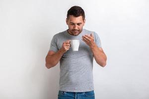 Buen hombre se para con una taza de té o café de la mañana y huele a aroma.- imagen foto