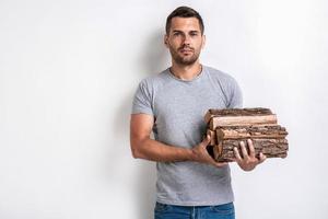 Handsome man stands over white studio background and holding a firewood.- Image photo