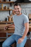 Handsome man sits on the chair leaned on table , smiling looking at the camera.- Image photo