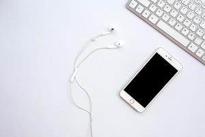 White office  desk with a smartphone, earphones   - Top view photo