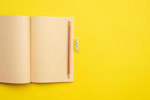 Open empty diary with a pencil and an  inscription idea on yellow background photo