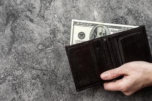 Male hand holding a pocket wallet  with  money. -Top view photo