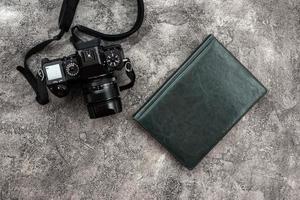 photocamera and a notebook lying on a plaster background