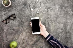 Top view plaster background with smartphone in male hand photo