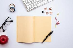 white desk with astationery, open empty diary and other objects on it photo