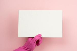 mano femenina con guante de látex rosa sosteniendo una maqueta en blanco blanco vacío foto