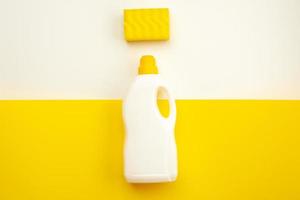 Botella de detergente con tapón amarillo y esponja sobre un fondo blanco-amarillo foto