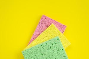 Three kitchen rag lying on yellow background. Top view photo