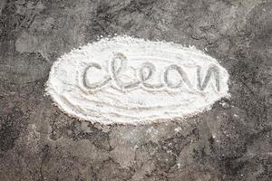 Scattered flour in form oval with inscription clean on a gray decorative plaster background.