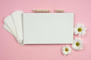 Female pads and white piece of paper on a pink background photo