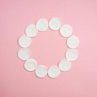 Clean white cotton stack of disc for beauty face hygiene with selective focus on pink neutral background. photo