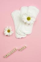 Woman pads  and chamomile  lying on  pink  background.    Concept critical days photo