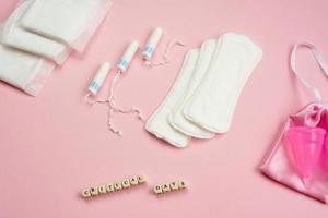 White tampons, menstrual cup, female gaskets on pink background. Concept of critical days, menstruation photo