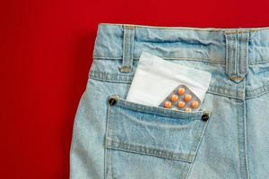 servilleta sanitaria de mujer en el bolsillo de los pantalones vaqueros. foto