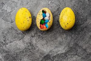 huevos de pascua con dulces sobre fondo gris foto