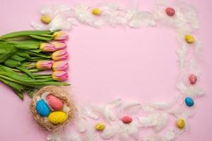 fondo rosa de pascua con chocolate, huevos de pascua, tulipanes, plumas foto