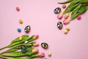 Easter pink background with chocolate rabbit, easter eggs and tulips.