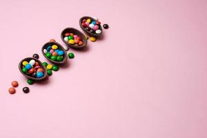 Fondo rosa pascua con caramelos multicolores en un nido de chocolate - copyspace foto