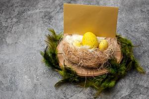 Bird's nest with eggs and blank leaf on wooden stand on gray background
