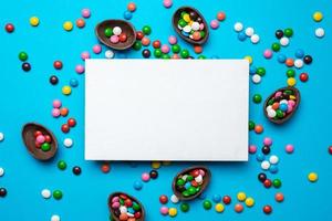 Empty mockup white blank on a blue  Easter background. Multi-colored candy. - Copyspace photo