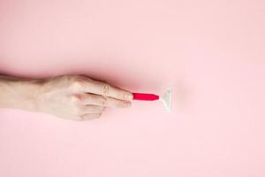 Woman hand holding razor blades. Isolated on pink background photo