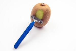 Kiwi fruit and razor on white background. Hair removal concept. Creative minimal concept with copy space. photo