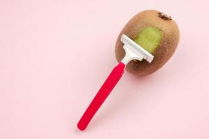 Kiwi fruit and razor on pink background. Hair removal concept. Creative minimal concept with copy space. photo